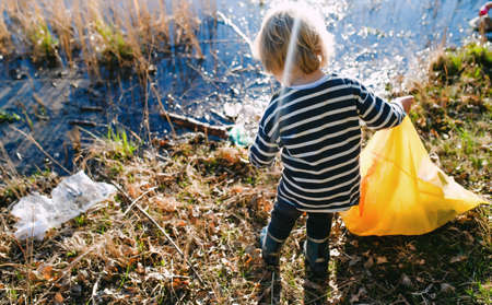 Unrecognizable small child collecting rubbish outdoors in nature, plogging concept.の写真素材