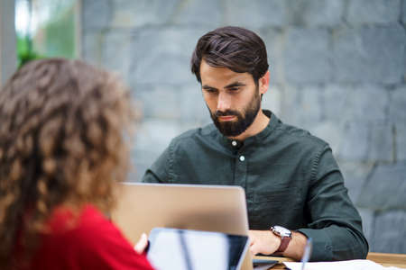 Young man and woman sitting indoors in office, working.の写真素材