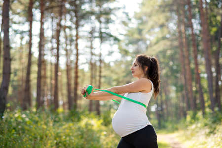 Portrait of happy pregnant woman outdoors in nature, doing exercise.の写真素材