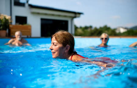 Portrait of senior woman in swimming pool outdoors in backyard.の写真素材