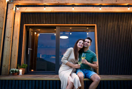 Young couple with wine outdoors, weekend away in container house in countryside.の写真素材
