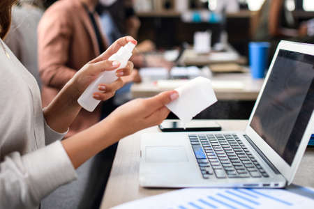 Unrecognizable woman disinfecting indoors in office, back to work after coronavirus lockdown.の写真素材