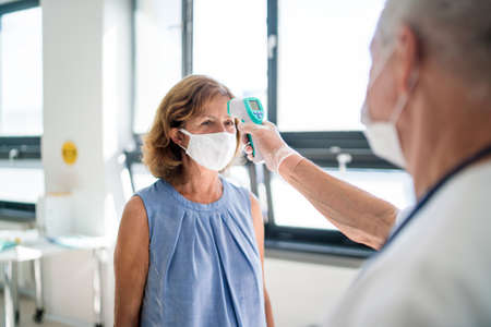 Doctor with face mask measuring temperature, coronavirus, covid-19, measuring temperature and...