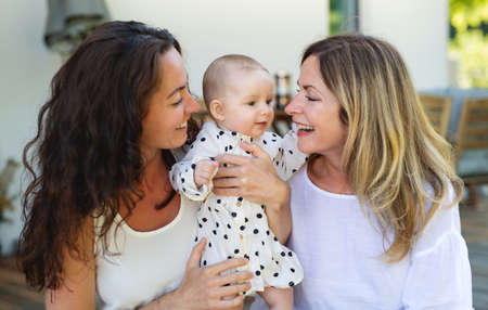 Woman with daughter and baby granddaughter resting outdoors in backyard.の写真素材