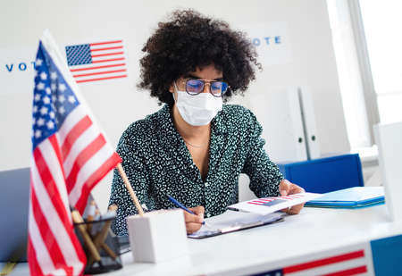 Member of electoral commission in polling place, usa elections and coronavirus.