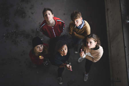 Top view of group of teenagers gang standing indoors in abandoned building, looking at camera.の写真素材