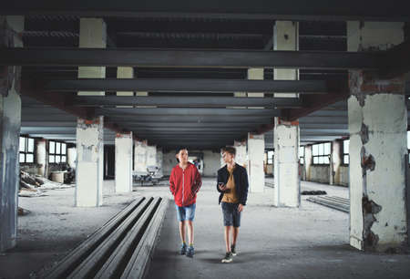 Teenagers boys gang indoors in abandoned building, using smartphone.の写真素材