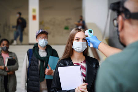 Young students back at college or university, coronavirus and measuring temperature concept.