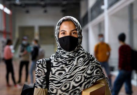 Islamic student with face mask back at college or university, coronavirus concept.の写真素材