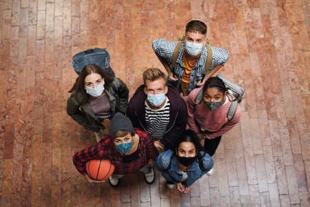 Top view of young students with face masks back at college or university, coronavirus concept.の写真素材
