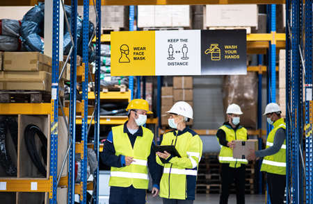 Group of workers with face mask working indoors in warehouse, coronavirus concept.の写真素材