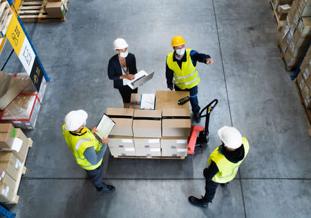 Top view of group of workers with manager working indoors in warehouse, coronavirus concept.
