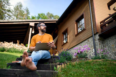 Mature man working outdoors in garden, home office concept.