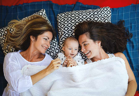 Top view of woman with daughter and baby granddaughter resting on blanket.の写真素材