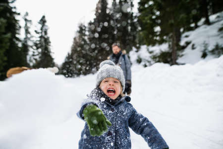 Front view of small child playing in snow, holiday in winter nature.