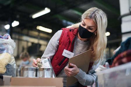 Woman volunteer in community charity donation center, food bank and coronavirus concept.