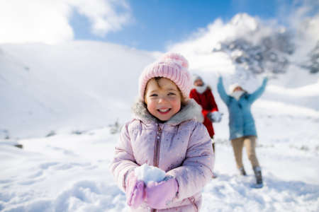 Portrait of cheerful small girl playing in snow in winter nature, playing.の写真素材