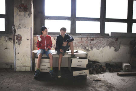 Group of teenagers boys indoors in abandoned building, talking.