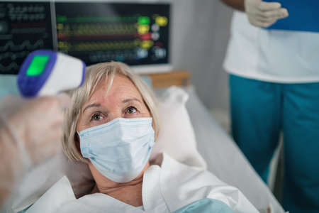 Doctor and covid-19 infected patient in bed in hospital, coronavirus and measuring temperature...