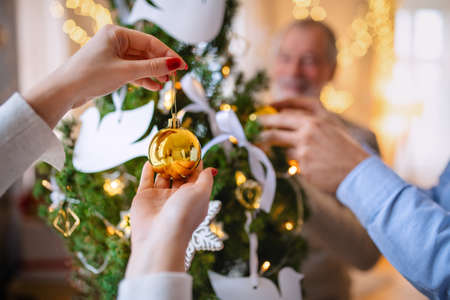 Unrecognizable family relatives indoors at home at Christmas, decorating tree.の写真素材