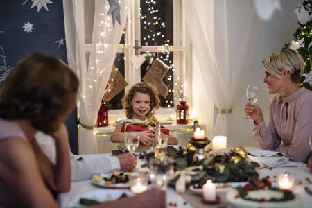Multi-generation family indoors celebrating Christmas together, sitting at table.の写真素材