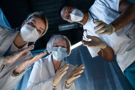 Bottom view of d doctors leaning over covid-19 patient n hospital, coronavirus and recovery concept.
