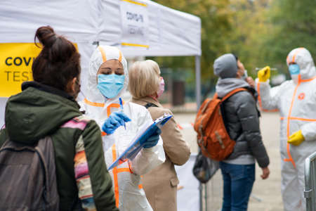 People waiting in covid-19 testing center outdoors on street, coronavirus concept.の写真素材