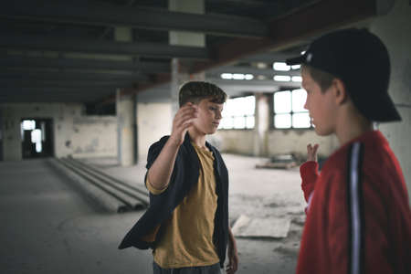 Teenagers boys indoors in abandoned building, greeting.の写真素材