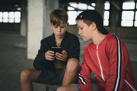 Group of teenagers boys indoors in abandoned building, using smartphone.の写真素材