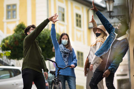 Group of young people outdoors in town, greeting. Coronavirus concept.