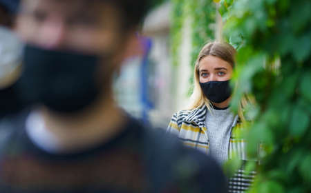 Young people queuing outdoors in town. Coronavirus and safe distance concept.