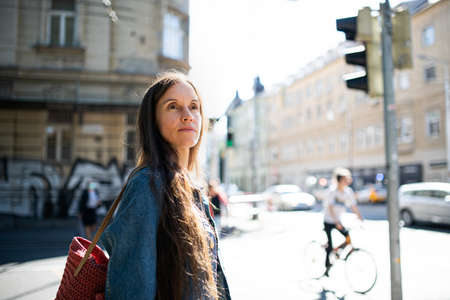 Mature woman walking outdoors in city or town park, crossing street.の写真素材