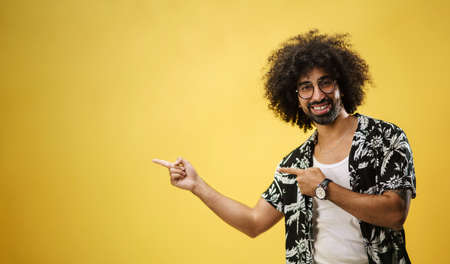 Portrait of mature man in a studio on yellow background, pointing fingers.