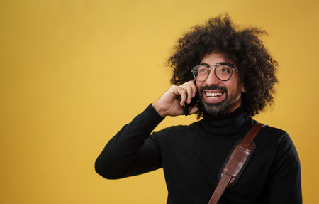 Portrait of mature man with smartphone in a studio on yellow background.の写真素材