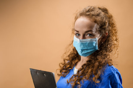 Young woman doctor in a studio holding clipboard, coronavirus concept.の写真素材