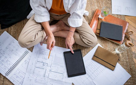 Top view of senior woman architect sitting on floor indoors at home, working.
