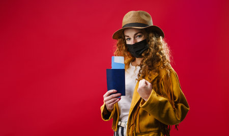 Young woman in a studio holding plane tickets, coronavirus and travelling concept.の写真素材