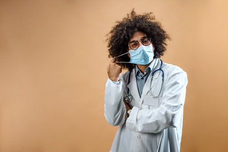 Happy mature man doctor with face mask in standing in studio, coronavirus concept.の写真素材
