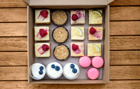Selection of colorful and delicious cake desserts in box on table, top view.の写真素材
