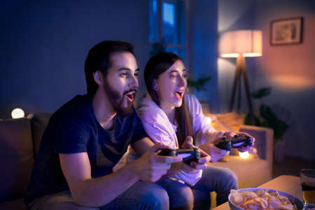 Young couple in love playing video games indoors at home.