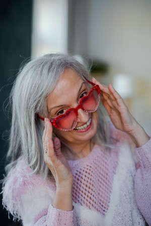 Portrait of senior woman with sunglasses indoors at home, laughing.の写真素材