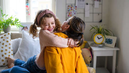 Sisters indoors at home, hugging. Lockdown concept.の写真素材
