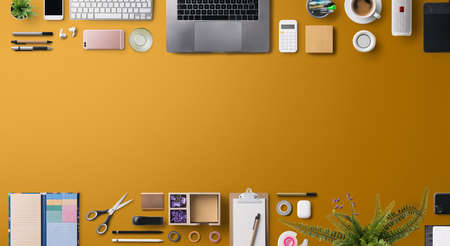 Flat lay top view office desk working space with laptop and supplies on orange background.の写真素材