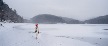 Active senior woman on walk outdoors in snowy nature, walking by frozen lake.の写真素材