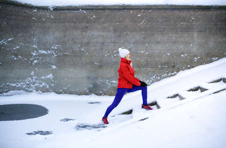 Active senior woman outdoors in snowy winter, doing exercise.