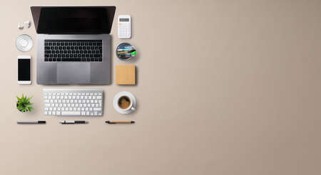 Flat lay top view office desk working space with laptop on brown background. Copy space.の写真素材