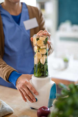 Unrecognizable caregiver or healthcare worker indoors, preparing smoothie food.