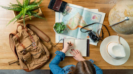 Top view of young woman with maps planning vacation trip holiday, desktop travel concept.