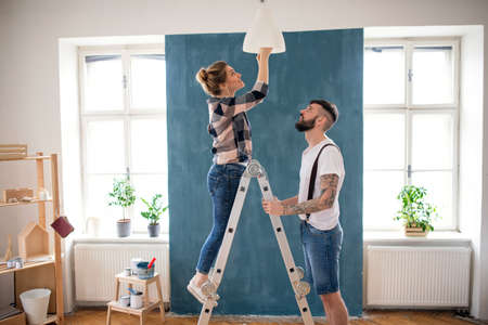 Mid adults couple changing light bulb indoors at home, relocation and diy concept.の写真素材
