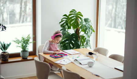 School girl sitting and working at table indoors at home, distance learning.の写真素材